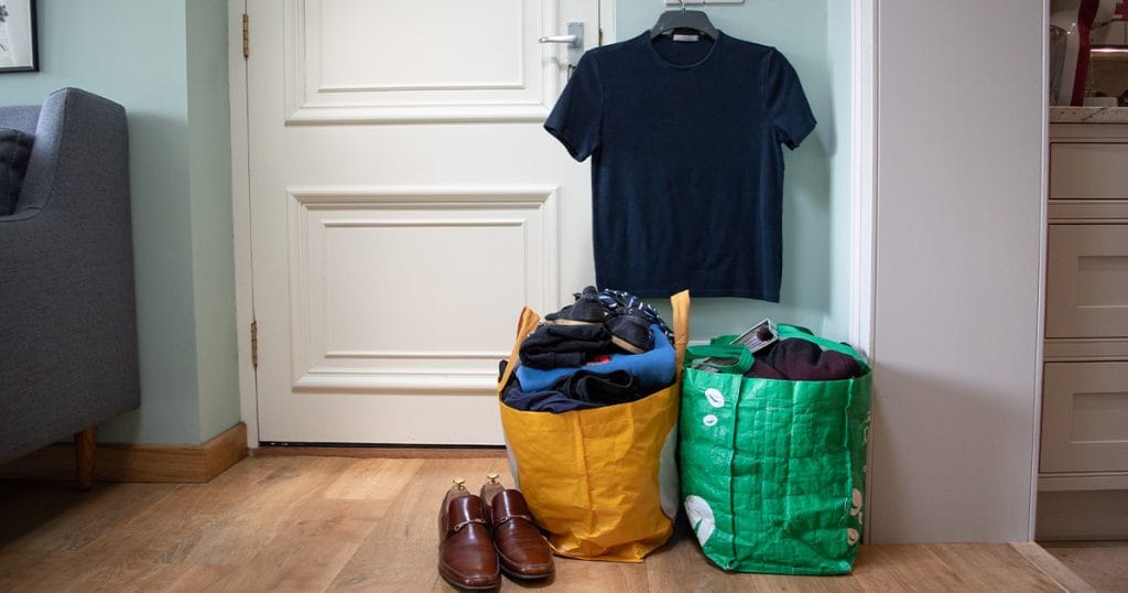 Clothes and shoes packed into bags, in front of a closed door