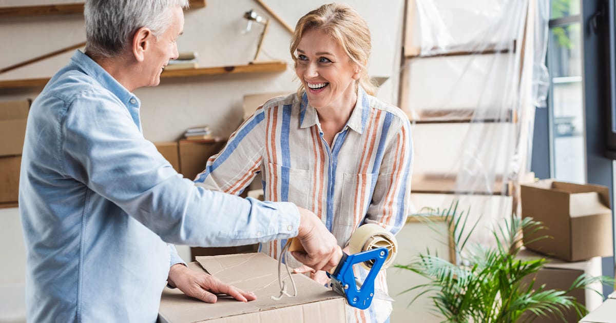 Over 50s couple smiling and packing boxes
