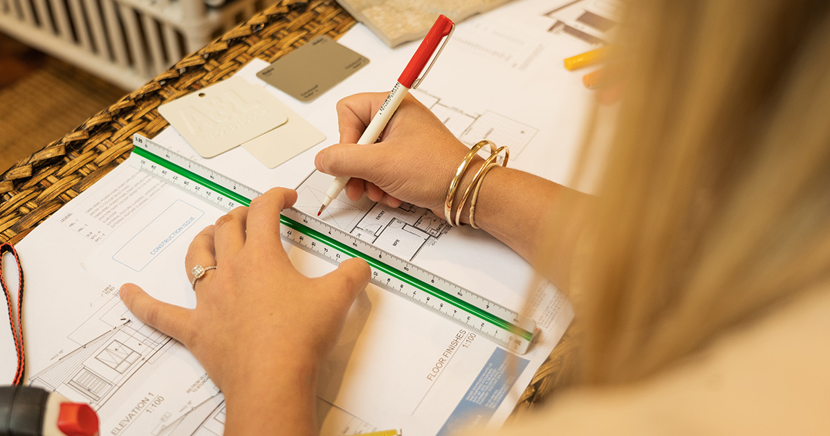 Over the shoulder shot of an interior design sketch and plan on a notebook