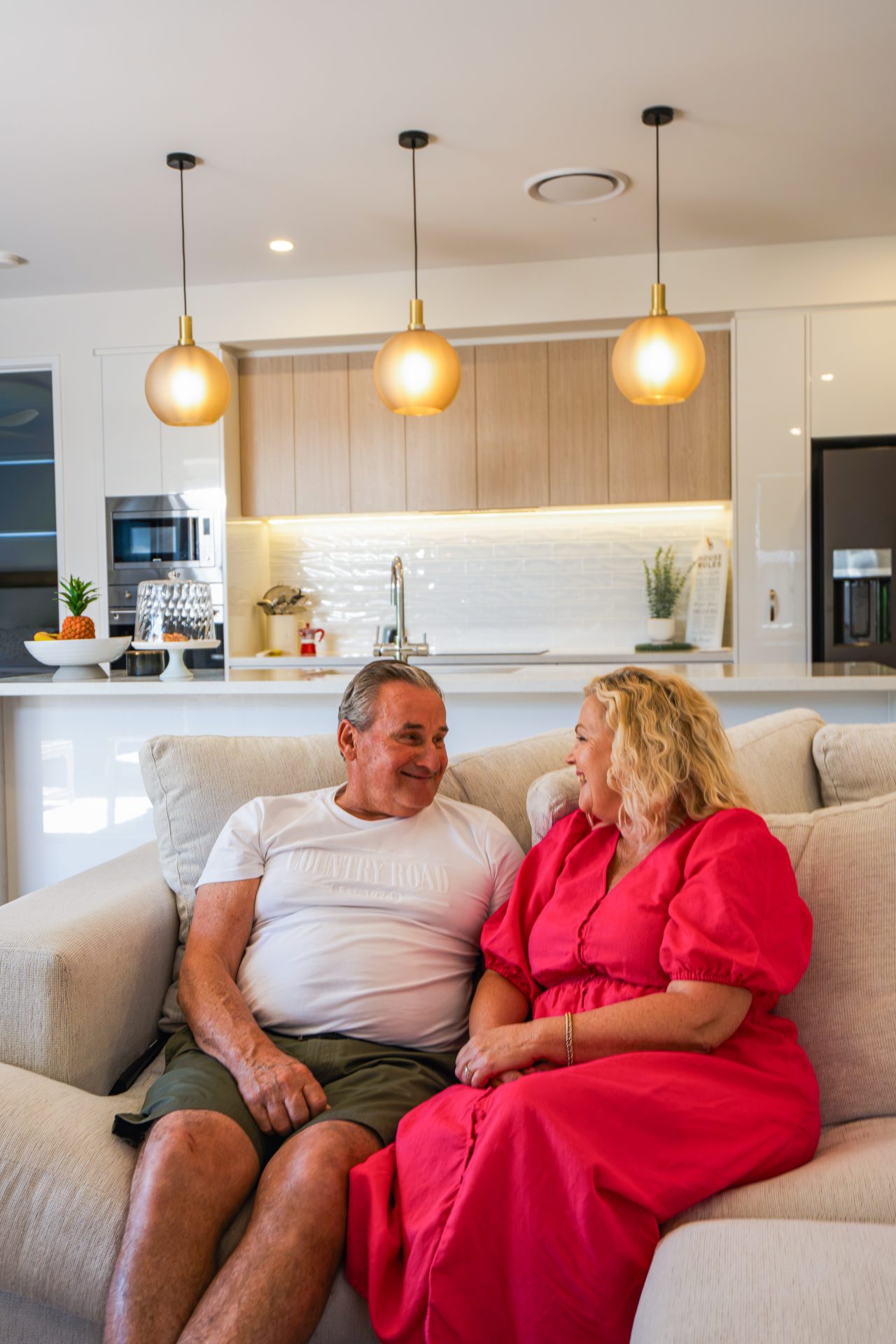 Living Gems Moreton Bay residents Will and Tina Fedder relaxing together on the sofa in their modern, open-plan villa.
