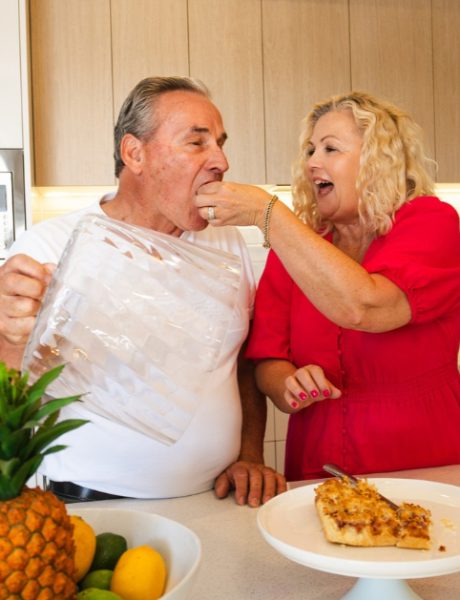 Living Gems Moreton Bay residents Will and Tina Fedder sharing a playful moment in the kitchen of their modern villa.